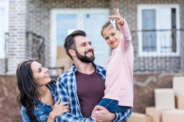 husband and wife holding daughter with house keys