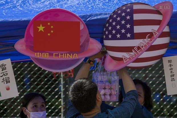 A vendor sets up foods and beverages at a booth displaying China and American flags