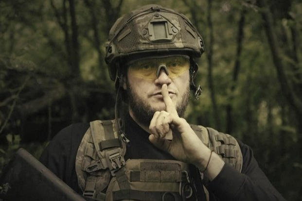 Ukrainian soldier poses for the camera with his fingers to his lips