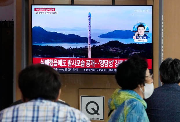 A TV screen shows an image of North Korea's rocket launch during a news program.