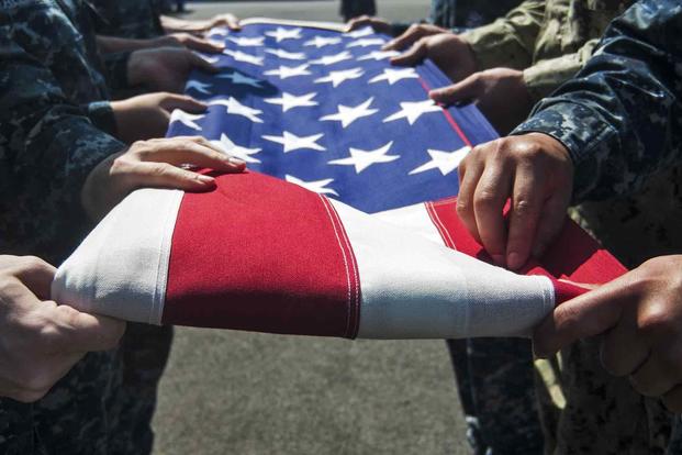 Navy sailors practice a six-man flag folding