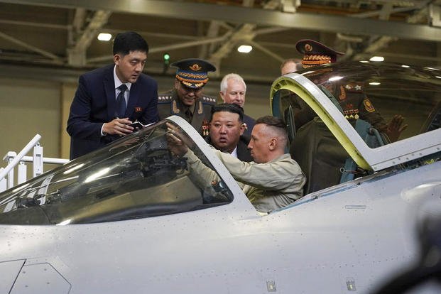 North Korean leader Kim Jong Un, center, looks at a military jet cockpit