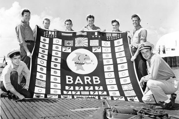 The 8 members of the USS Barb’s demolition squad pose with the submarine’s battle flag at Pearl Harbor in August 1945.