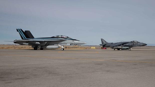 A Naval F/A-18E Super Hornet, left, and a Marine AV-8B Harrier II prepare to takeoff during cold weather training at Naval Air Station Fallon, Nevada, February 4, 2020.