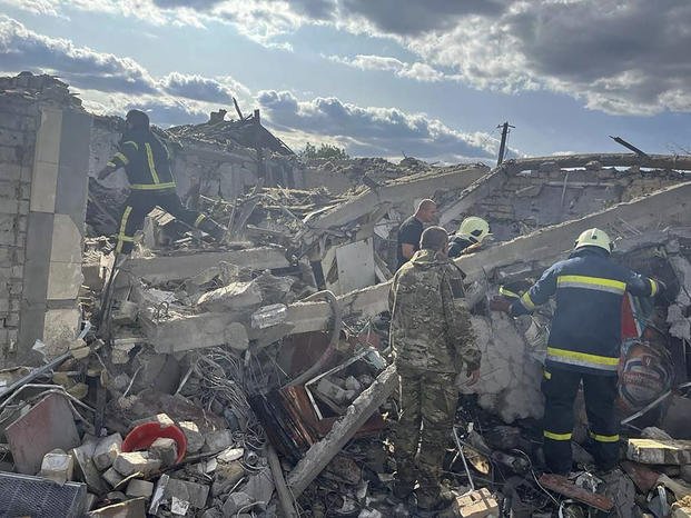 In this photo provided by the Ukrainian Presidential Press Office, emergency workers search the victims of a Russian rocket attack that killed at least 47 people in the village of Hroza near Kharkiv, Ukraine.