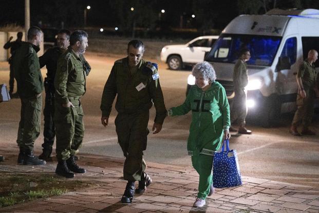 Ruth Munder, a released Israeli hostage, walks with an Israeli soldier shortly after her arrival in Israel