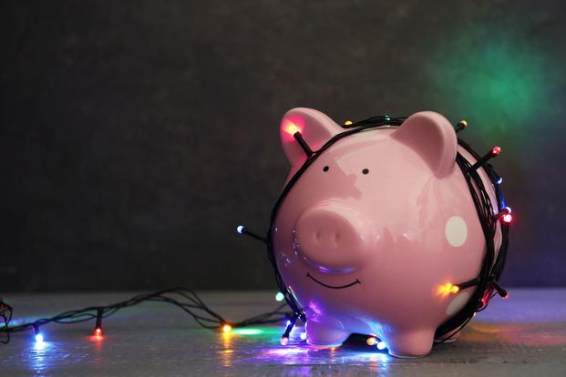 A string of holiday lights wind around a piggy bank