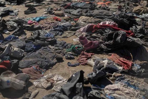 Clothes left behind by migrants are scattered by the bank of the Rio Grande