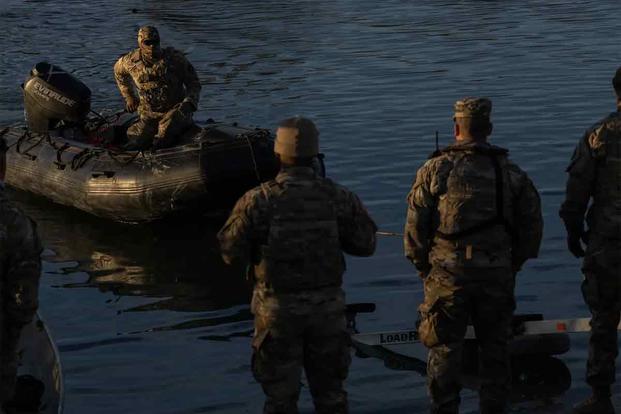 Texas Guard members guide a raft on the bank of the Rio Grande