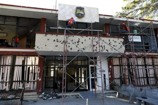 Workers repair a City Hall riddled in large bullet holes in Villa Union, Mexico