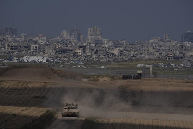 Israeli soldiers move on the top of a tank near the Israeli-Gaza border