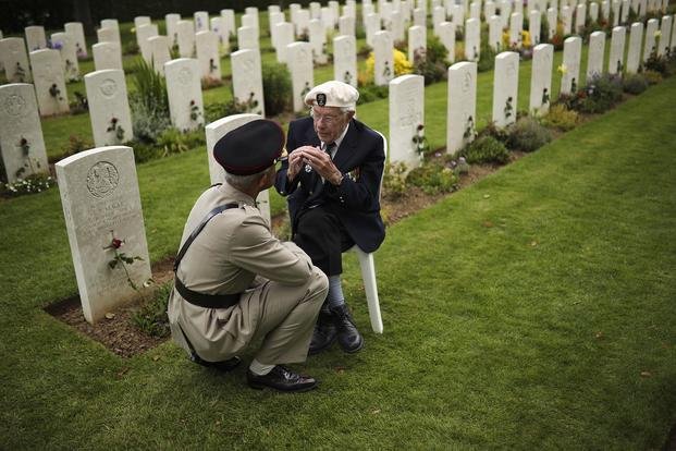 A World War II veteran talks to a soldier at the end of a ceremony to mark the 75th anniversary of D-Day at the Bayeux War Cemetery in Bayeux, Normandy, France, on June 6, 2019. (Francisco Seco/AP File Photo)
