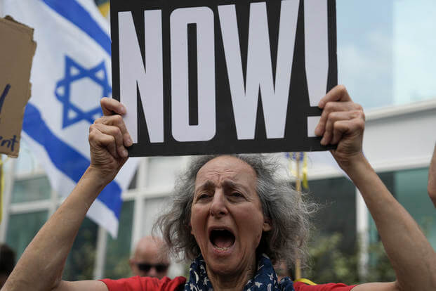 A woman holds a banner and shouts slogans with families and supporters of Israeli hostages held by Hamas in Gaza