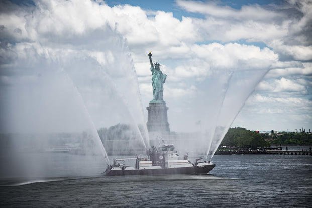 A New York City Fire Department vessel renders honors, through a water salute, to the Statue of Liberty in New York City for Fleet Week 2018.