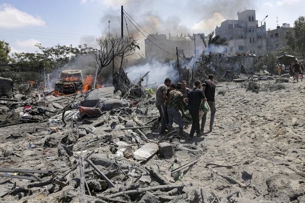 Palestinians evacuate a body from a site hit by an Israeli bombardment.