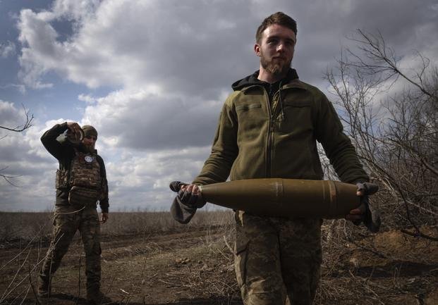 Ukrainian soldiers carry shells to fire at Russian positions on the front line