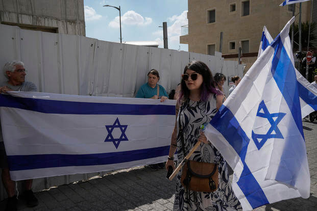 Mourners wave Israeli flags.