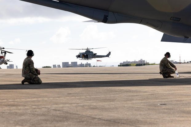 U.S. Air Force Staff Sgt. Michael Keller, right, flying crew chief of 909th Aircraft Maintenance Unit, and Senior Airman Mark Morales, an aircraft electrical and environmental systems specialist with the 909th AMU, observe UH-1Y Venom before takeoff procedures on Marine Corps Air Station Futenma, Okinawa, Japan.