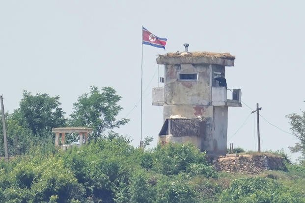 A North Korean soldier stands at the North's military guard post as a North Korean flag flutters in the wind, seen from Paju