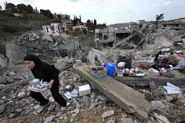 A woman collects the remains of her destroyed house. 