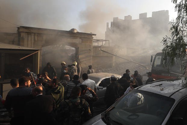 Security officers and rescuers gather at a destroyed building hit in an Israeli airstrike in Damascus