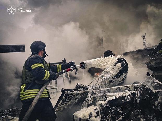 rescue workers extinguish a fire of a building destroyed by a Russian strike in Brovary