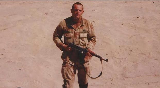 Army paratrooper Bill Glose, young, grim-faced and holding an AK-47 in Iraq -- the photo that would grace the cover of his first book of poetry, 'Half a Man.' 