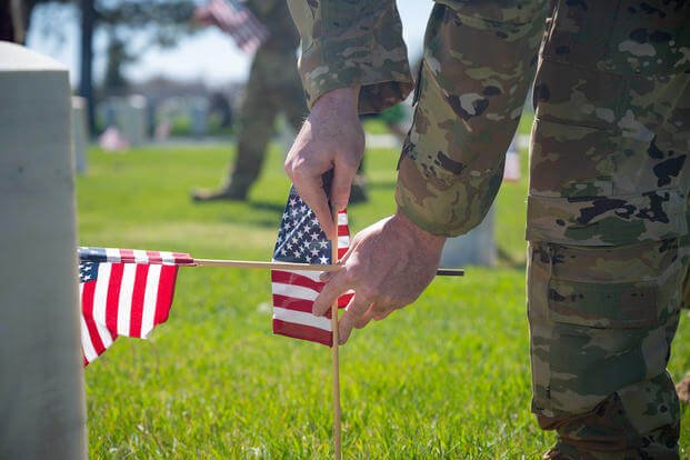 An airman places an American flag in front of a headstone in the base cemetery during the “Flags In” ceremony on F.E. Warren Air Force Base, Wyoming. 