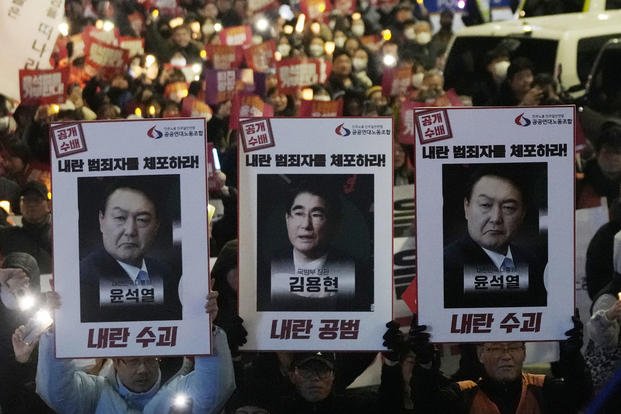 Protesters with images of South Korean President Yoon Suk Yeol and former South Korea Defense Minister Kim Yong Hyun, center, march to the presidential office after a candlelight vigil against President Yoon in Seoul, South Korea, on Dec. 5, 2024. The signs read 'Arrest the rebellion criminals.' 