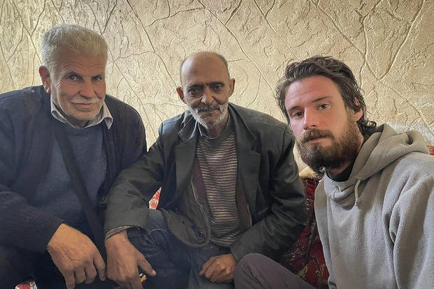  American Travis Timmerman, right, sits with Mosaed al-Rifai, center, who found him in the Syrian desert