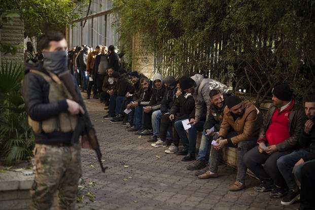 Members of Bashar Assad's army line up to register with Syrian rebels in Damascus, Syria.