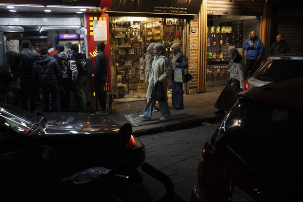 People walk past shops on a street in Damascus, Syria.