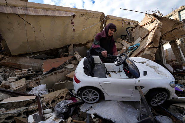 Mariam Kourani removes a toy car from the rubble of her destroyed house.