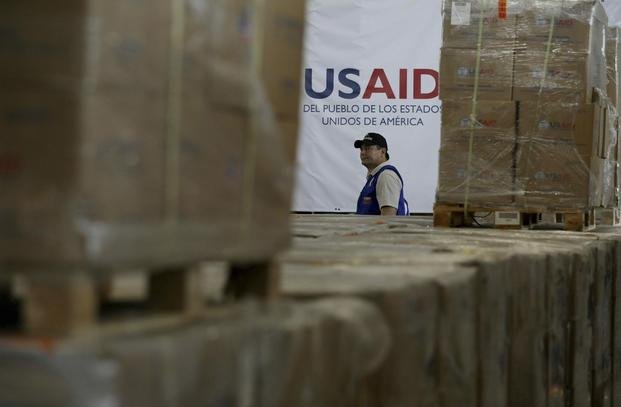 A man walks past boxes of USAID humanitarian aid at a warehouse at the Tienditas International Bridge
