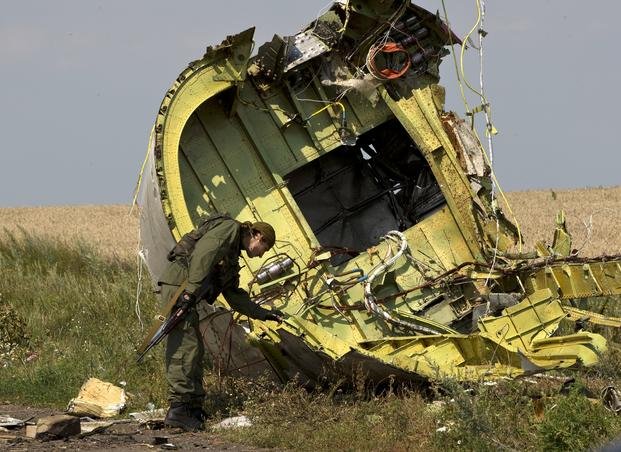 A pro-Russian rebel touches the MH17 wreckage at the crash site of Malaysia Airlines Flight 17