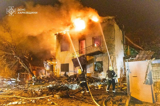emergency services personnel work to extinguish a fire following a Russian attack in Kharkiv
