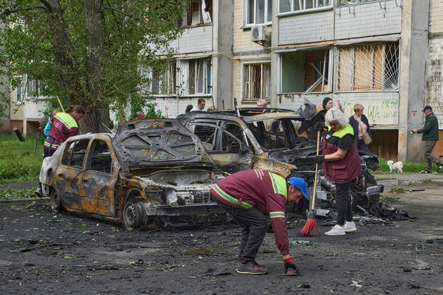 Municipal workers clean up around burnt cars