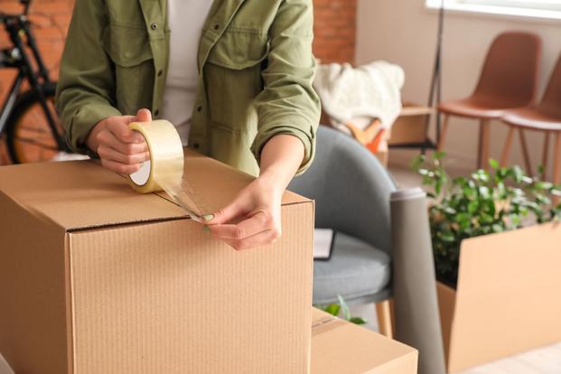 A woman's arms appear taping a box closed.