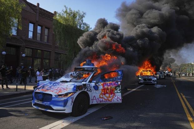 Waymo taxis burn near the Metropolitan Detention Center of downtown Los Angeles