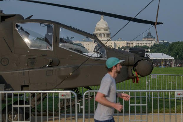 A man passes by a military helicopter parked on the National Mall