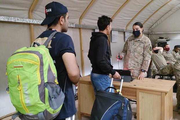 U.S. Army soldiers help Afghan evacuee interpreters through the registration process on a U.S. military base in Kuwait.