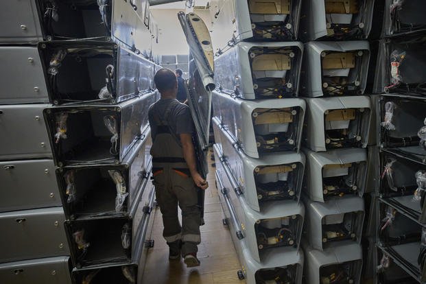 A worker carries part of a combat drone at Fire Point's secret factory in Ukraine