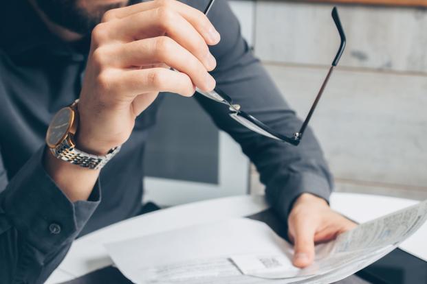Holding glasses, looking at papers.