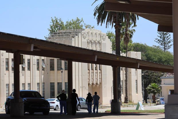 People are silhouetted against a historic building that has been marked for improvement at the West Los Angeles Veterans Affairs Medical Center campus, where President Trump's executive order is directing the Department of Veterans Affairs to set a goal of housing up to 6,000 homeless veterans at the center. (Allen J. Schaben/Los Angeles Times)