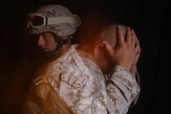 Stressed soldier with head in hands.