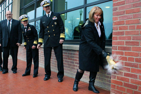 Beverly Hilarides, in the time-honored tradition of Navy shipbuilders, christens the Humphreys Building, Building 197, during a ceremony at the Washington Navy Yard. (U.S. Navy photo by Scott Adam Webb/Released)