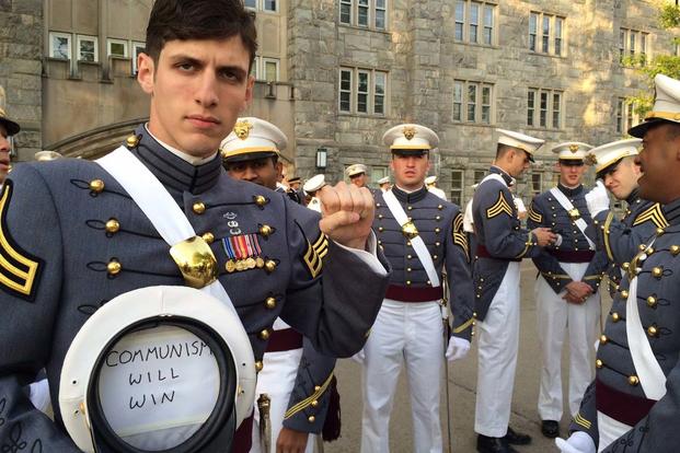 Second Lt. Spenser Rapone is seen in an undated photo making a fist and holding a cap with a sign inside that reads, "Communism will win." (Twitter)