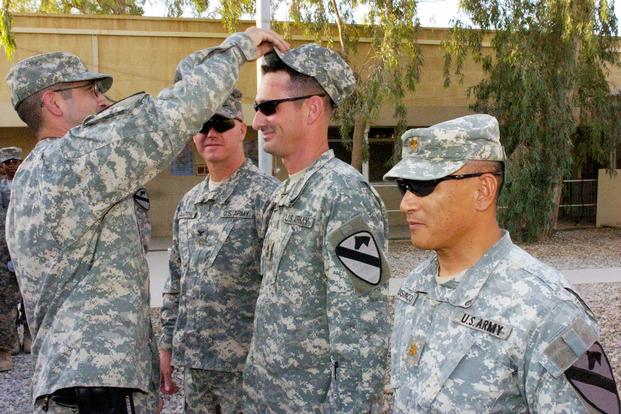 First Sgt. John Palido presents Master Sgt. Kenneth Stone with his new patrol cap during his promotion ceremony on Forward Operating Base Marez. (U.S. Army/Sgt. Chris Kozloski)