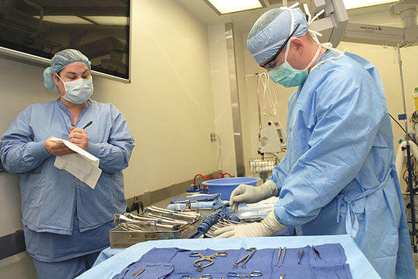 R.N. Valerie Haddle and Nurse Technician Sgt. Robert Larkin perform an inventory of the instruments that are laid out for surgery. (U.S. Army/Rachael Tolliver)