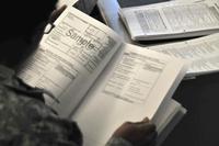 A soldier reads through a tax preparation booklet. (U.S. Army/ Mike Strasser, Fort Drum Garrison Public Affairs)